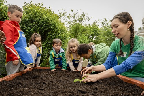 Ein Teammitglied der EDEKA Stiftung zeigt Kita-Kindern bei 