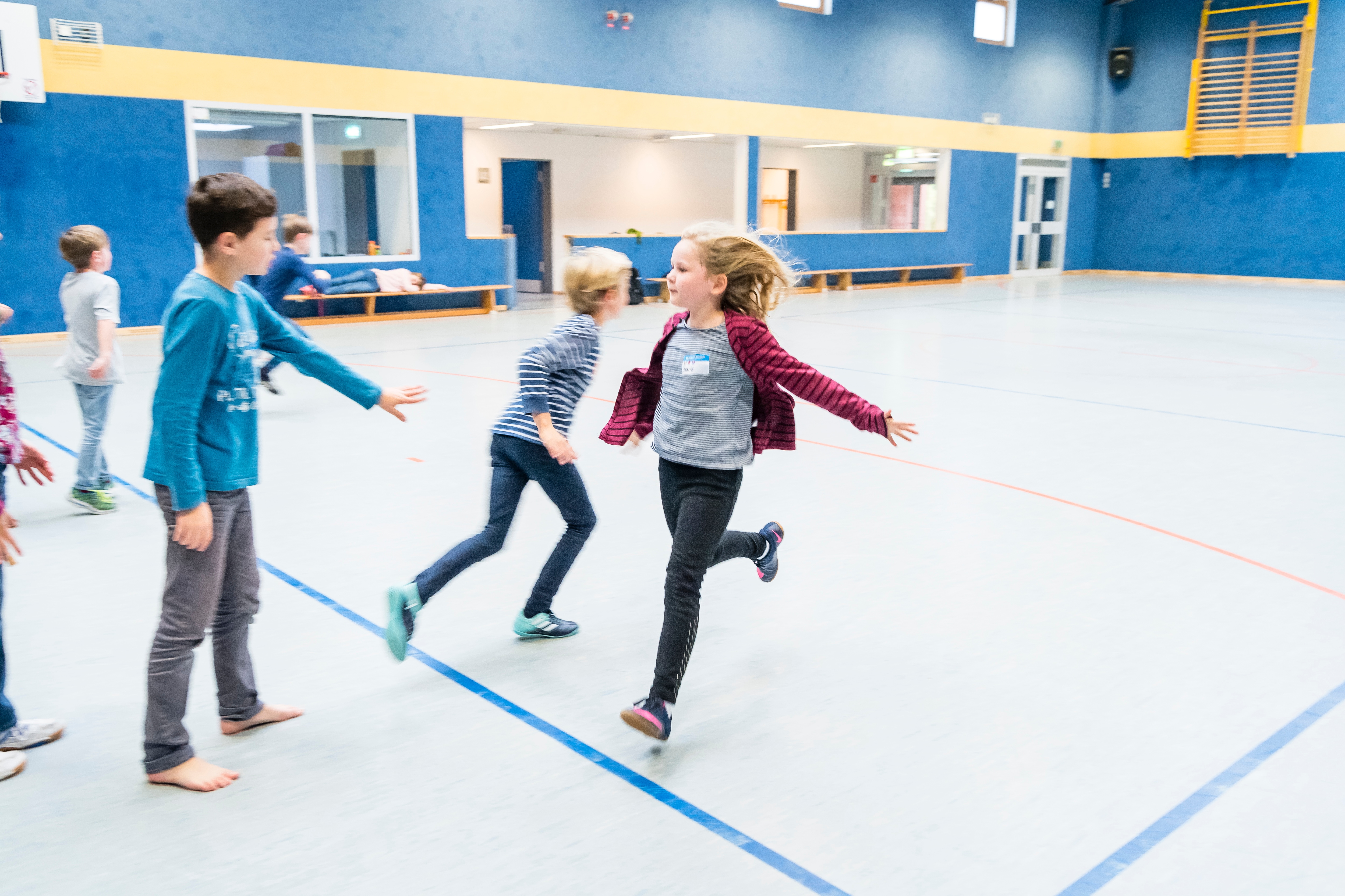 Kinder spielen ein Bewegungsspiel in der Turnhallte am Projekttag "Mehr bewegen - besser essen" der EDEKA Stiftung.