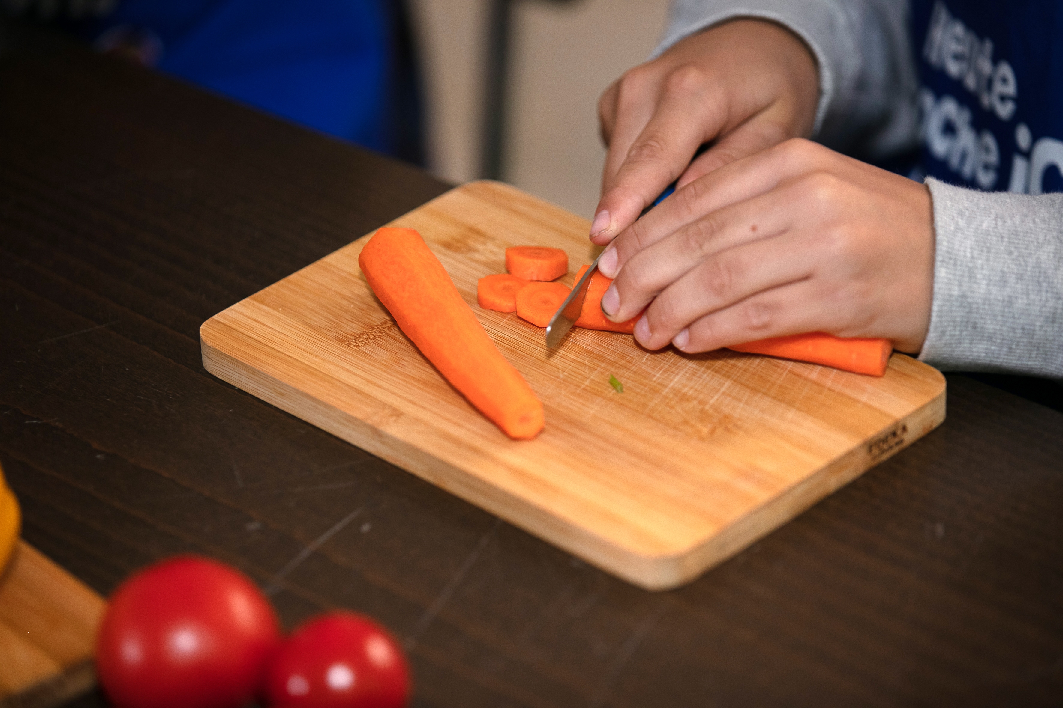 Kinderhände schneiden Gemüse am Projekttag "Mehr bewegen - besser essen" der EDEKA Stiftung.