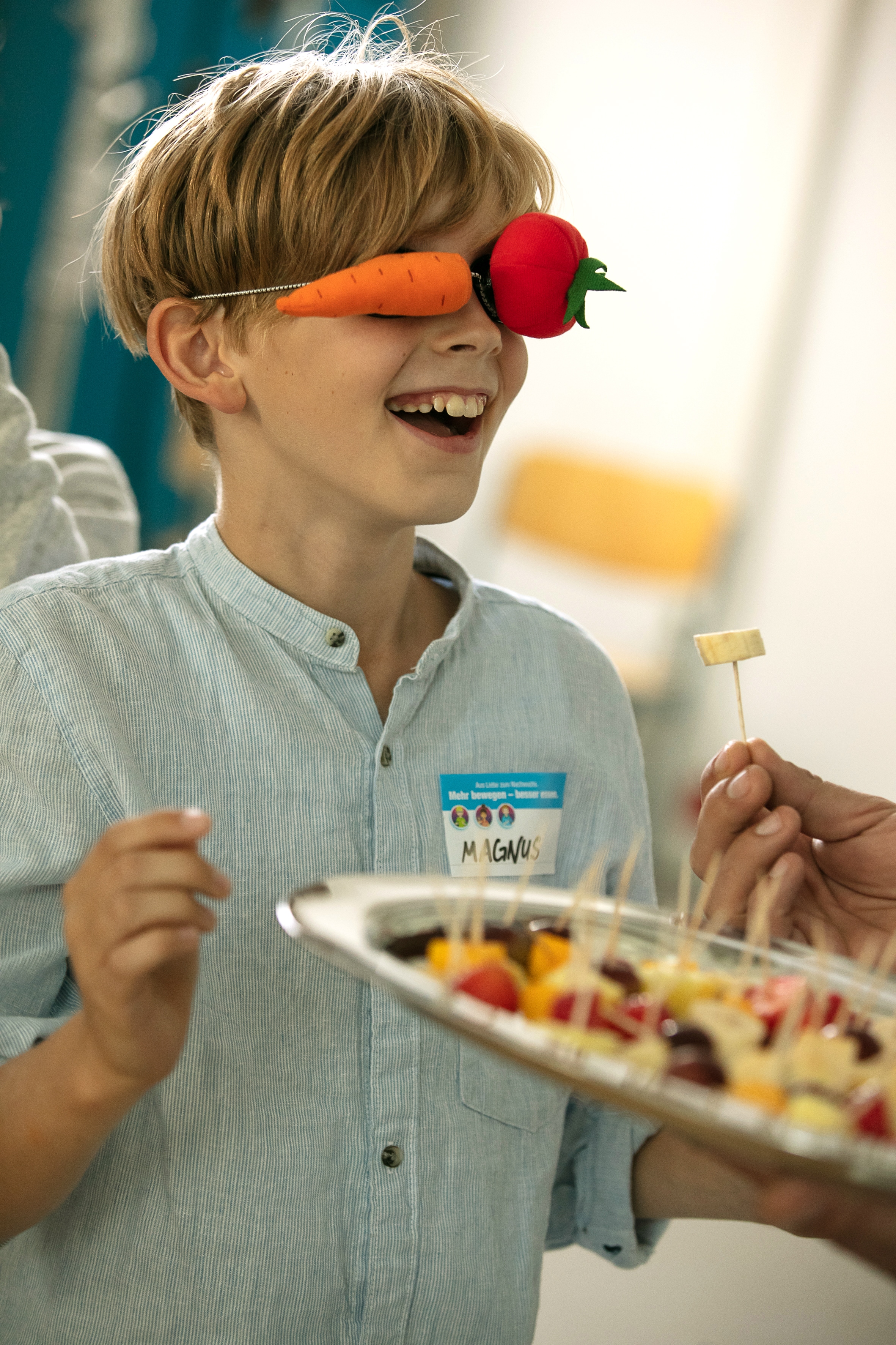 Ein Schüler ist bereit beim Sinnesparcour von "Mehr bewegen - besser essen" mit verbundenen Augen ein Obststück zu probieren.